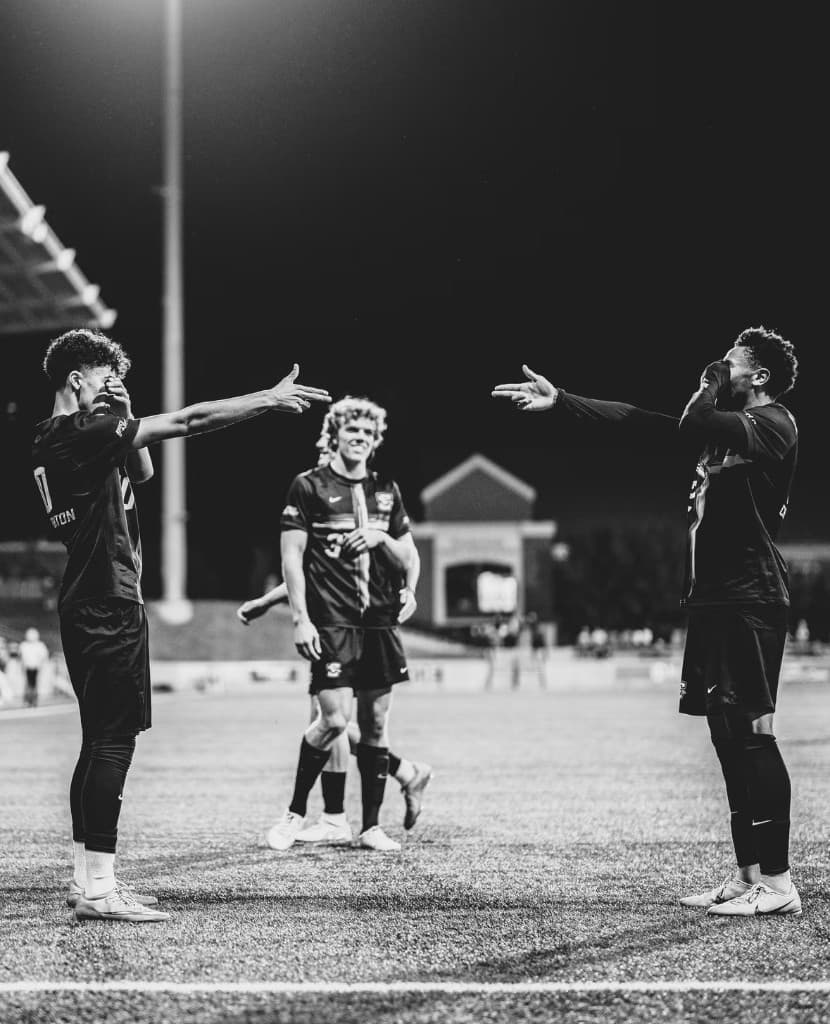 A player with arms outstretched on the field at night